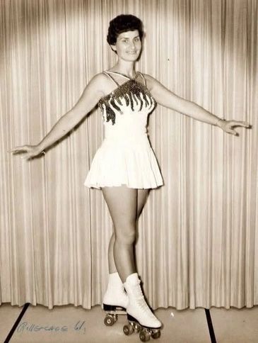 Woman posing in vintage roller skates and dress.