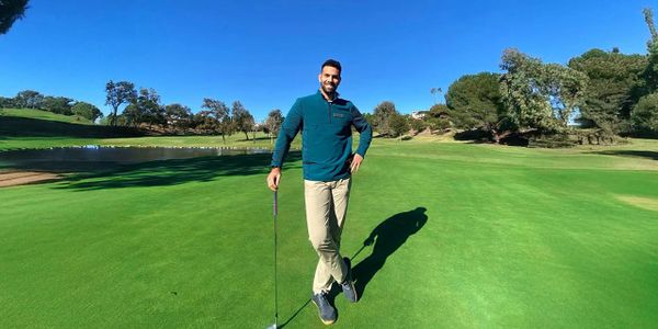 Man standing on a golf course holding a golf club.
