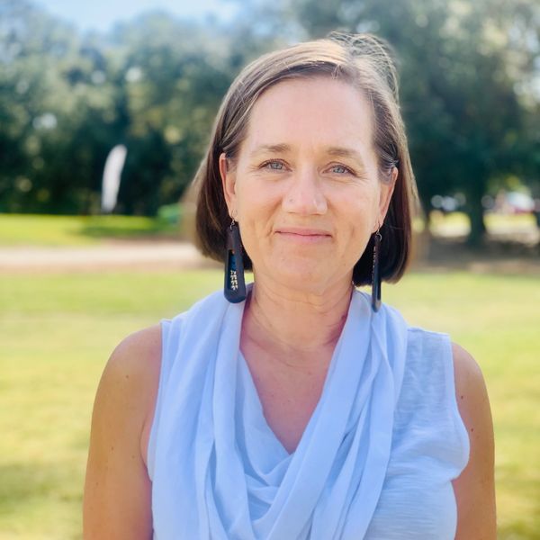 Woman outdoors in light blue top and earrings.