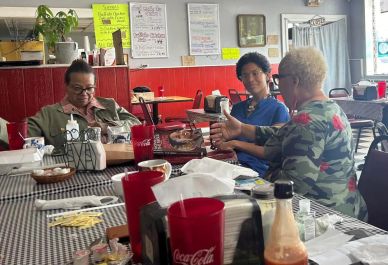 Three people chatting around a table at a casual restaurant.