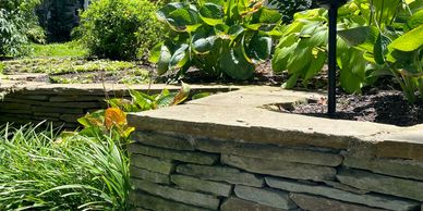 Natural stone retaining wall with landscaped planting beds enhancing beauty and functionality.