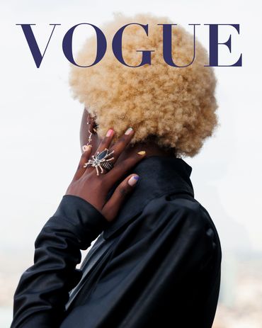 Fashion-forward individual with blonde afro and statement rings on Vogue cover.