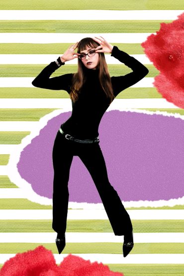 Woman in black outfit posing with glasses against colorful striped backdrop.