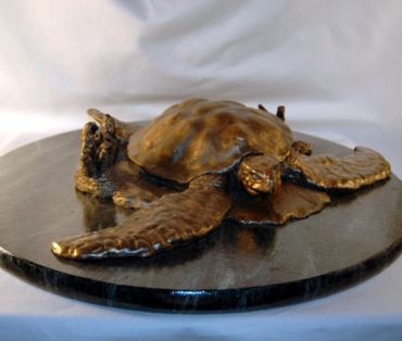 Bronze sculpture of a sea turtle on a round base.