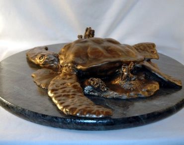 Bronze sculpture of a sea turtle on a round base.