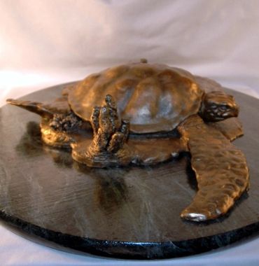 Bronze sculpture of a turtle on a dark base.