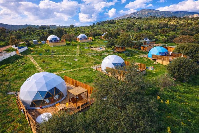 Eco-friendly dome homes in a scenic green landscape with hills and blue skies.