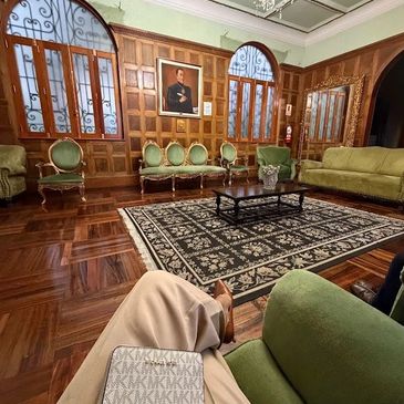 Elegant vintage living room with green furniture and wooden paneling.