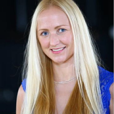 Smiling blonde woman with long hair wearing a blue top.