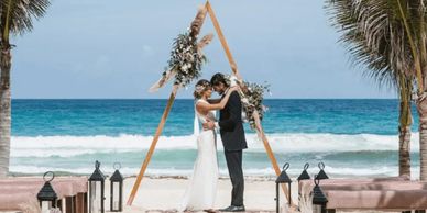 Romantic beach wedding setup with white chairs, floral décor, and ocean views
