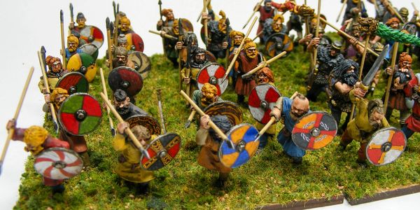 Painted miniature Viking warriors with shields and spears on a grass base.