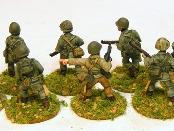 Miniature soldiers posed on grassy bases, ready for battle.