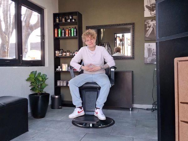 A person sitting confidently in a modern barbershop chair.