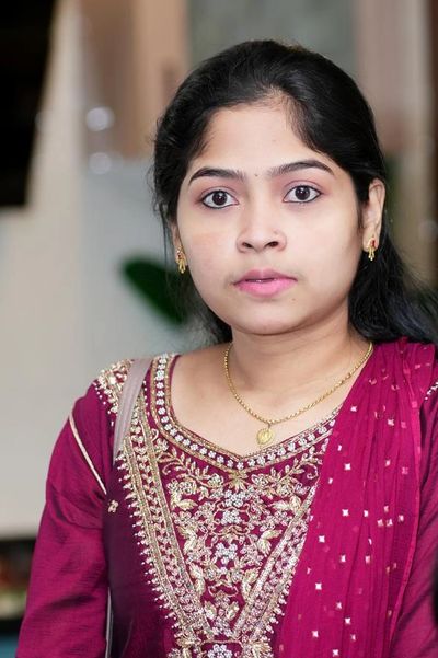 Young woman in a maroon embroidered traditional outfit.