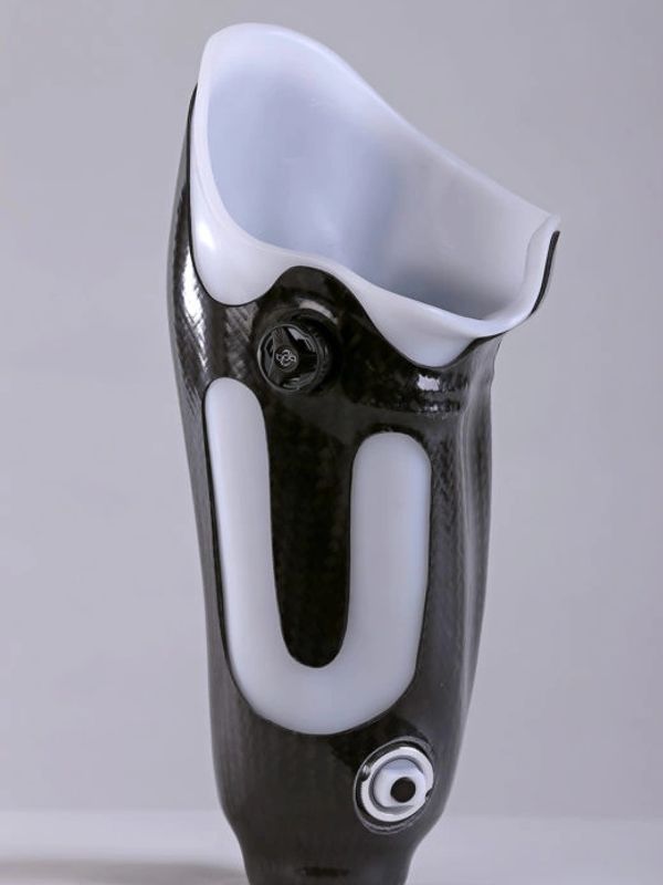 A sleek carbon fiber prosthetic leg socket with white padding.