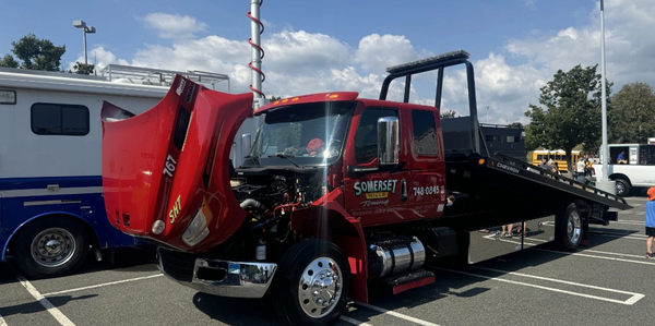 Red Somerset Hills tow truck with open hood in a parking lot on a sunny day.