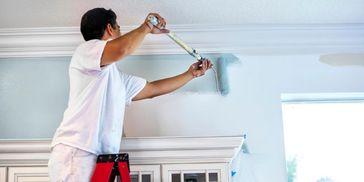 A man painting a wall light blue using a roller.