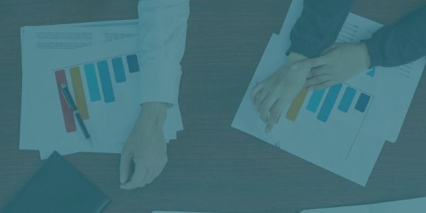 Hands over charts with bar graphs and pen on table.