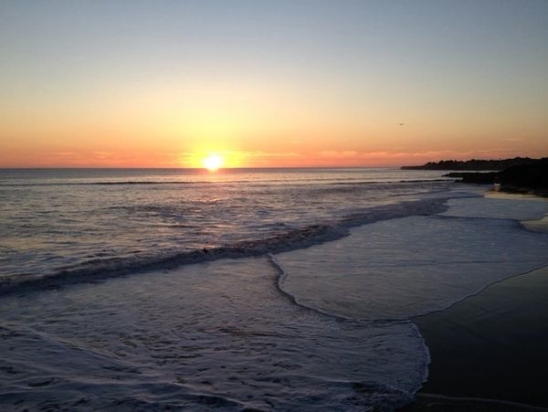 Serene sunset over the calm ocean waves at the beach.