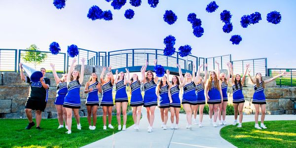 Cheerleaders tossing blue pom-poms in celebration.