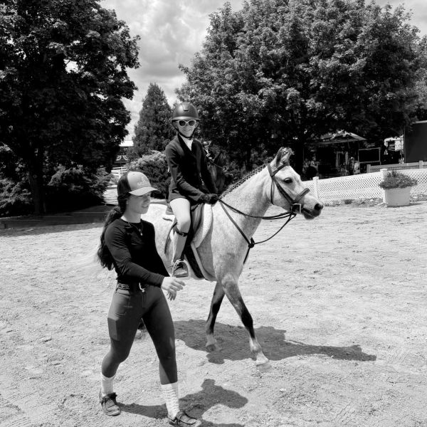 Child riding a horse with an instructor walking beside.