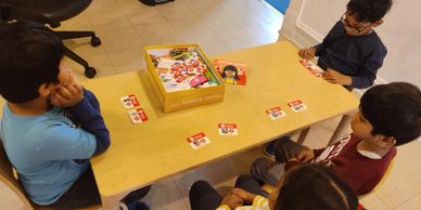 Four children playing a card game around a table.