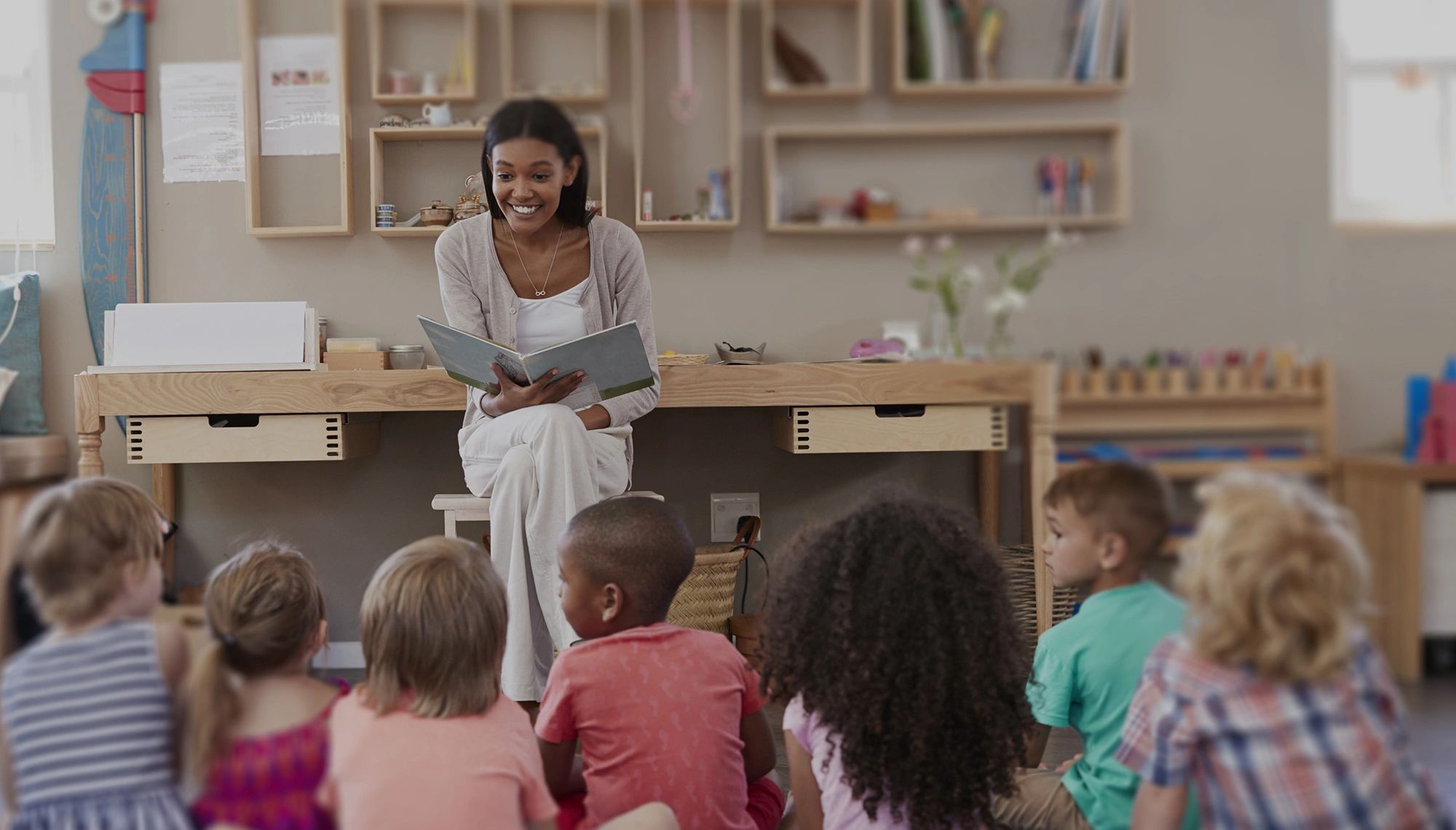 Teacher reading a book to children in a classroom.