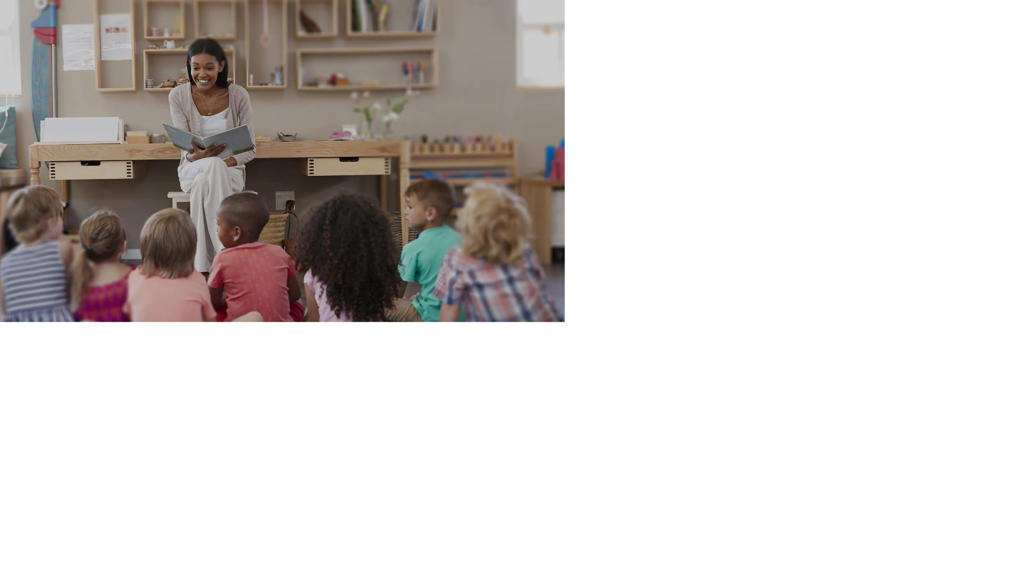 Teacher reading a book to children in a classroom.
