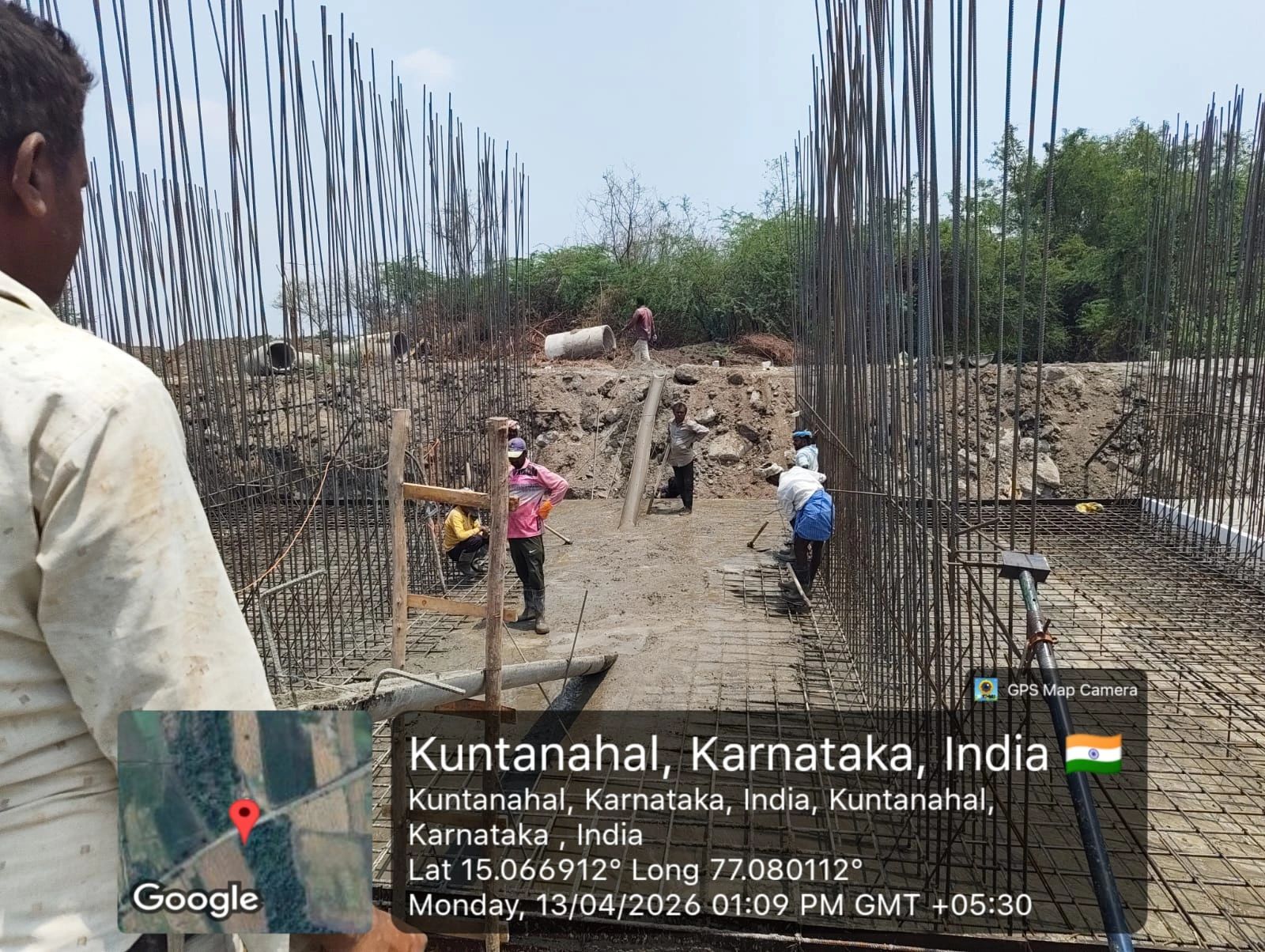 Construction workers laying concrete foundation with steel reinforcements in Kuntanahal, Karnataka, India.