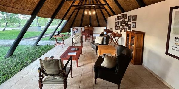 Cozy open-air lounge with wooden furniture and a thatched roof.