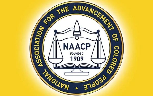The NAACP logo with scales of justice and founding year 1909 on a yellow background.