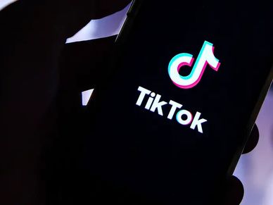 Hand holding phone displaying TikTok logo on screen.