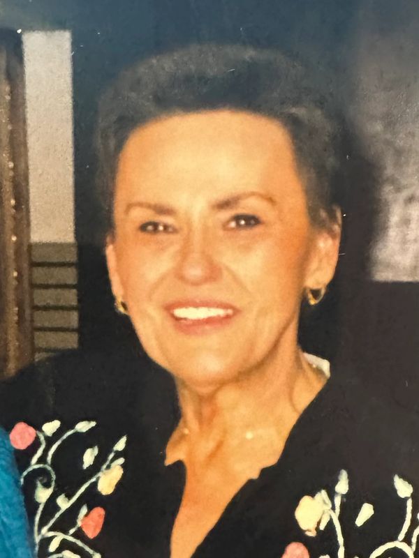 Smiling woman with short hair and floral-patterned black top.