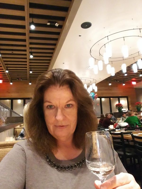 Woman holding a wine glass in a restaurant with modern lighting.