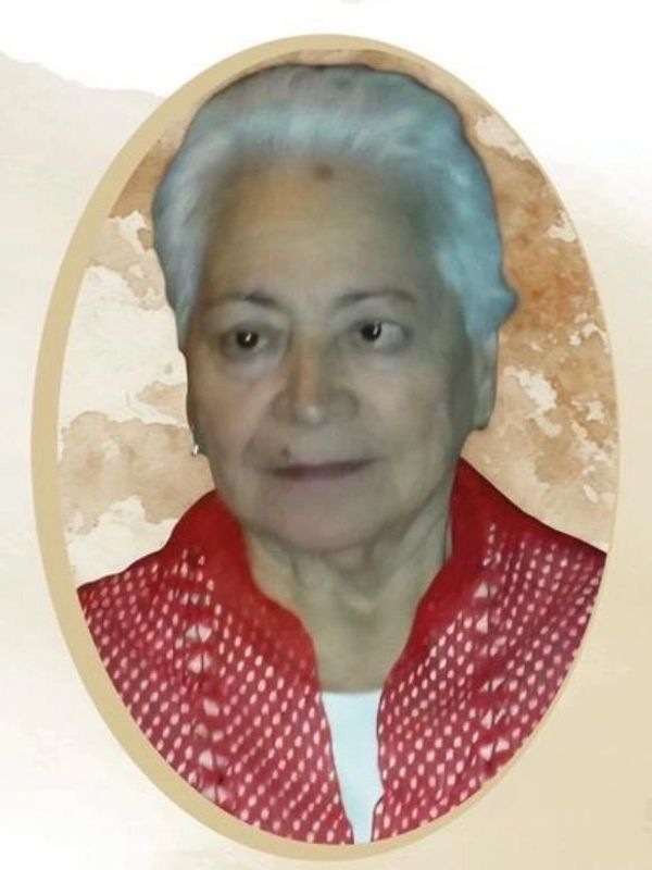 Portrait of an elderly woman with white hair and a red patterned top.