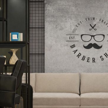 Modern barber shop waiting area with beige sofa and stylish decor.