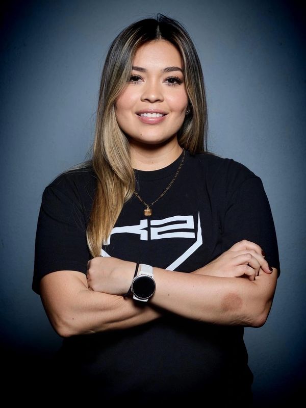 Young woman with long hair smiling, wearing a black graphic t-shirt and a smartwatch.