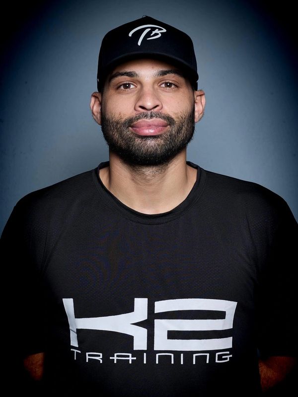 Man wearing a black cap and K2 Training shirt against a dark background.