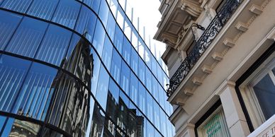 Contrast between modern glass building and classic architecture in black and white.