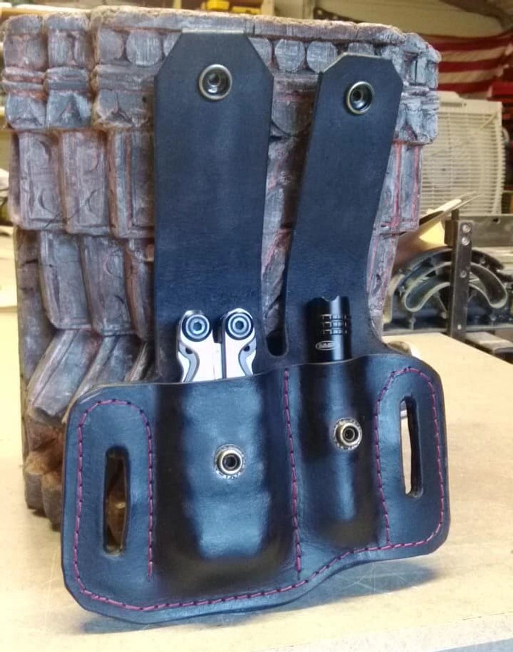 Porta herramientas de cuero con bordes cosidos en rojo.