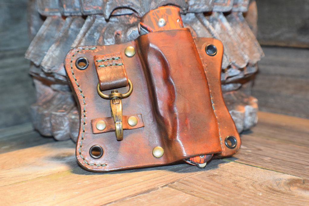Funda de cuero marrón con clip dorado sobre mesa de madera.