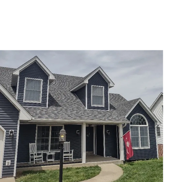 Blue house with white trim and a front porch with rocking chairs.