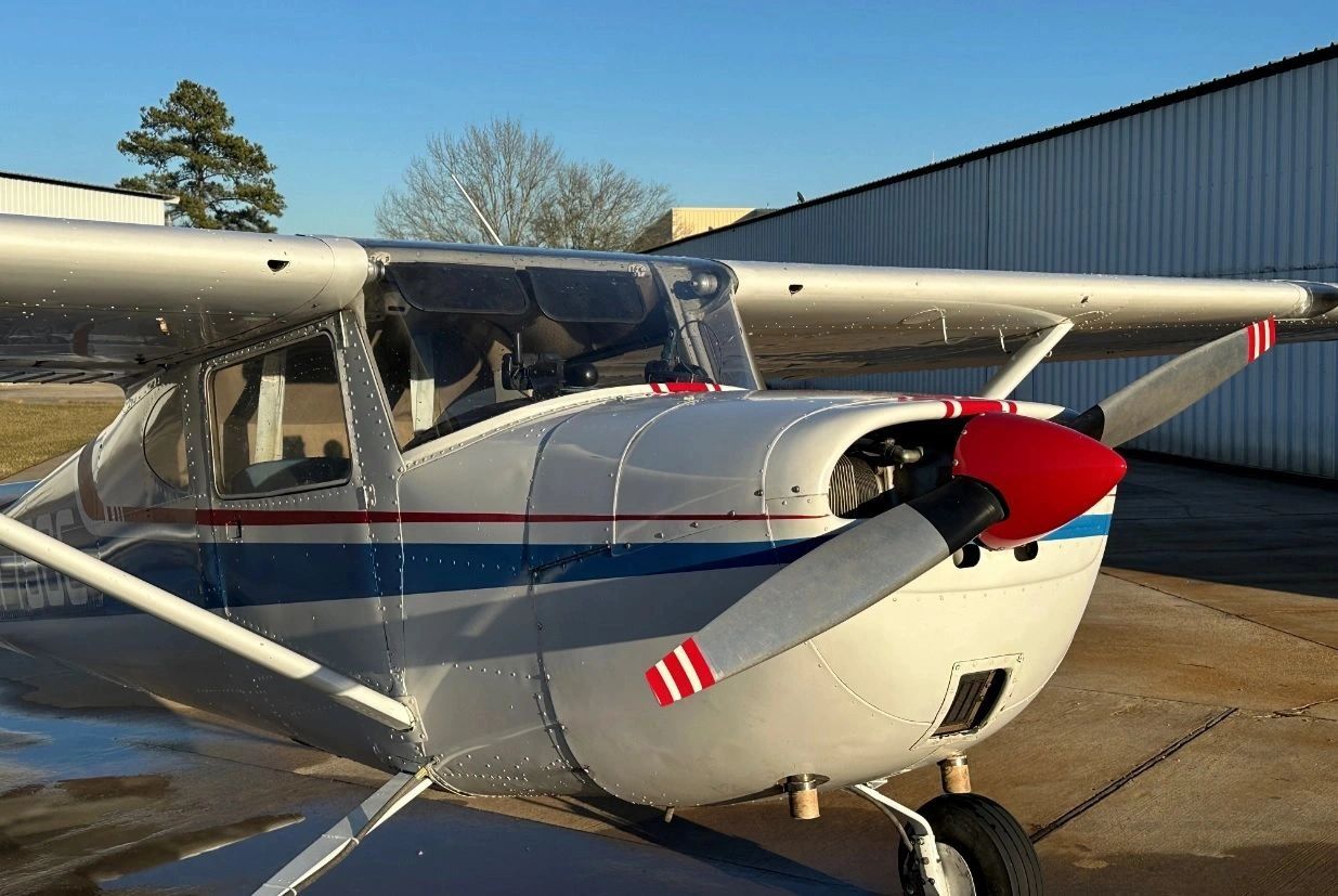 Small single-engine airplane with red, white, and blue stripes on a sunny day.
