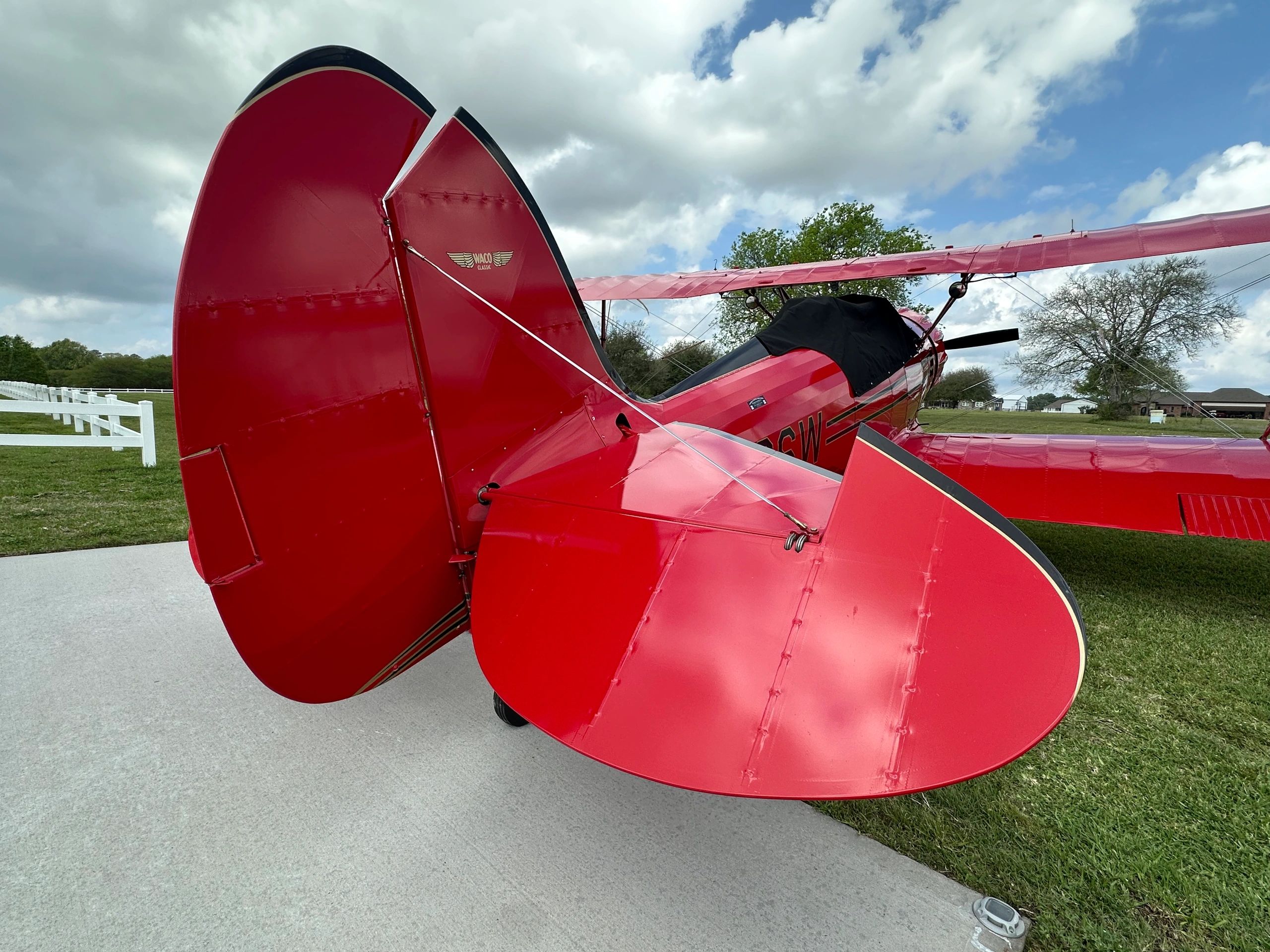 Rear view of a classic red Waco biplane on a concrete surface.