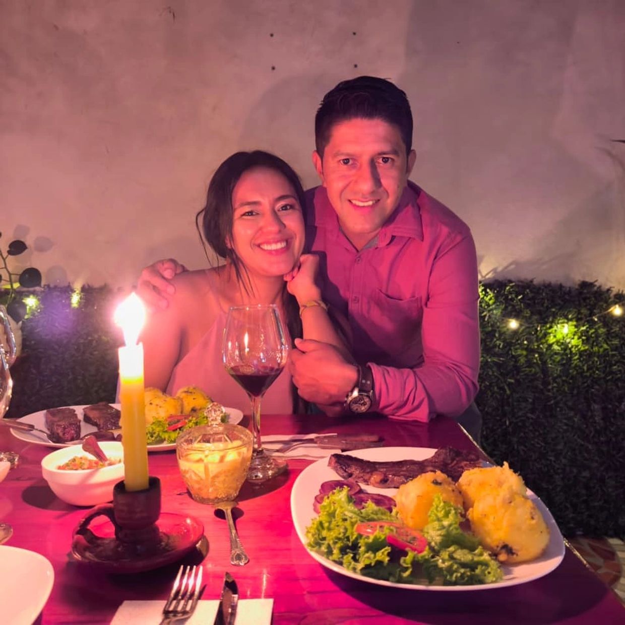 Couple enjoying a romantic candlelit dinner with steak and wine.