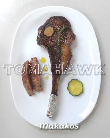 Grilled tomahawk steak with sausages and a slice of zucchini on a white plate.