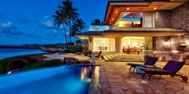 Luxurious beachfront villa with infinity pool and palm trees at twilight.