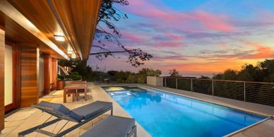 Modern outdoor pool area with sunset views and lounge chairs.