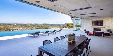 Modern outdoor dining area with infinity pool overlooking scenic landscape.