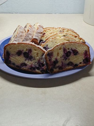 Sliced blueberry loaf cake and glazed pastries on a blue plate.